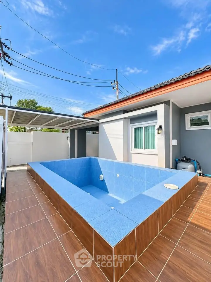 Modern home exterior with a stylish blue-tiled pool and sleek design under a clear sky.