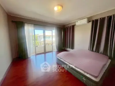 Spacious bedroom with large windows and balcony access, featuring hardwood floors and air conditioning.