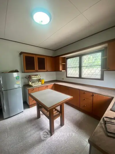 Spacious kitchen with wooden cabinets and natural light, perfect for culinary enthusiasts.