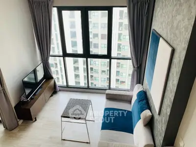 Modern living room with large windows and stylish decor in high-rise apartment.