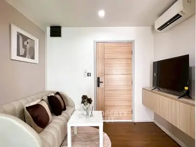 Modern living room with stylish decor and wall-mounted TV, featuring a cozy sofa and air conditioning.