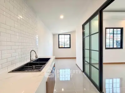 Modern kitchen with sleek design and open layout, featuring a stylish sink and large windows for natural light.