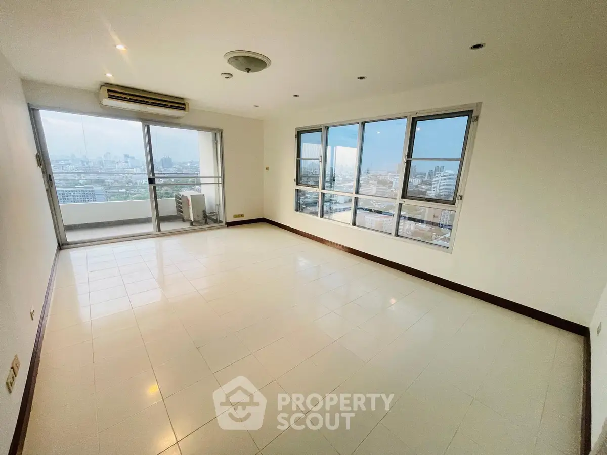 Spacious living room with panoramic city views and large windows in modern apartment.