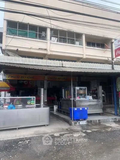 Street view of commercial property with food stalls and signage, ideal for business opportunities.