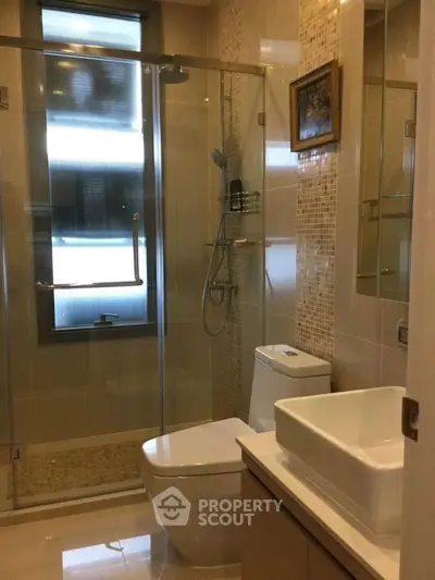 Modern bathroom with glass shower, sleek fixtures, and elegant tile design.