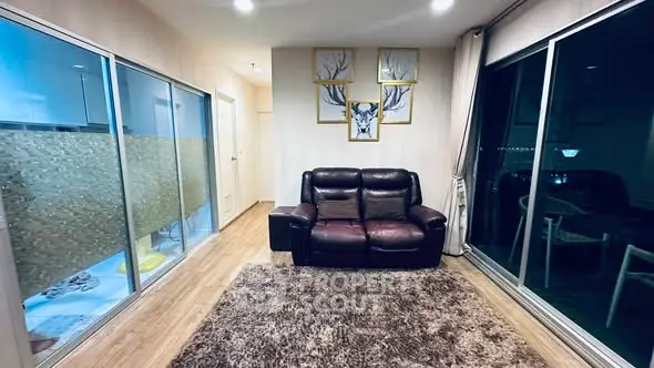 Modern living room with leather sofa, large windows, and stylish decor in a cozy apartment.