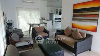 Modern living room with stylish furniture and vibrant artwork, featuring an open kitchen layout.
