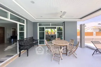 Spacious outdoor patio with elegant wooden furniture and ceiling fan, perfect for relaxation and entertaining.