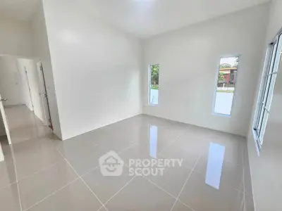 Spacious empty room with glossy tiled floors and large windows offering natural light.
