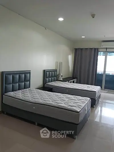 Spacious bedroom with twin beds and modern decor in a well-lit apartment.