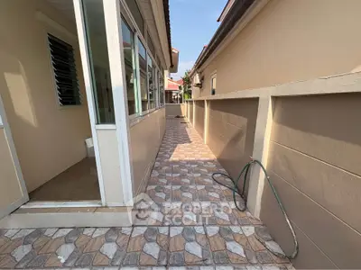 Charming exterior walkway with tiled flooring and garden hose, perfect for outdoor activities.