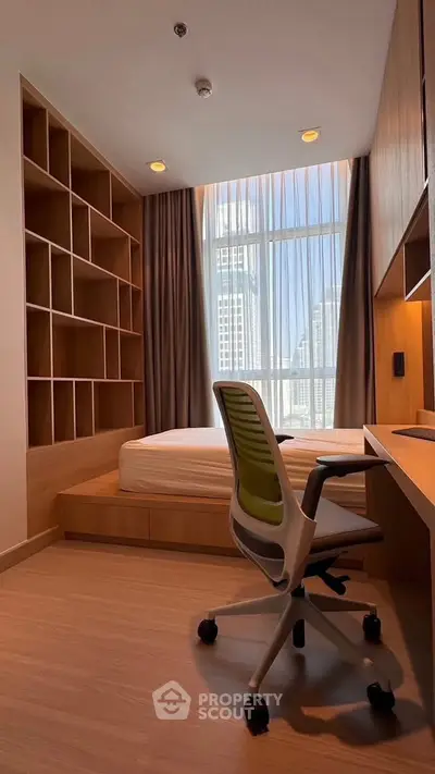Modern bedroom with built-in shelving and city view, featuring a sleek desk and ergonomic chair.