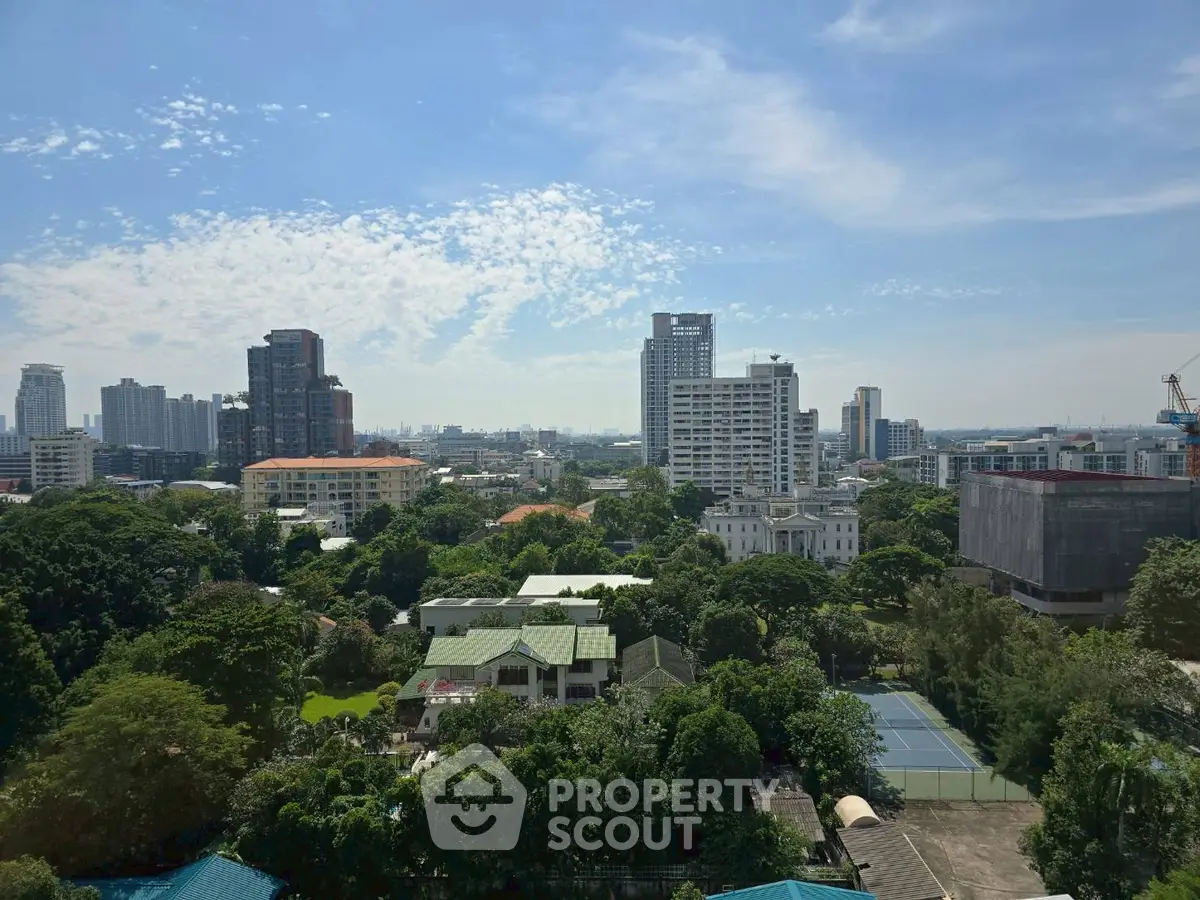 Stunning cityscape view with lush greenery and modern high-rise buildings under a clear blue sky.