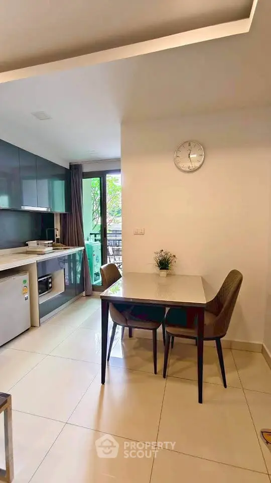 Modern kitchen with dining area, sleek cabinetry, and natural light from balcony view.