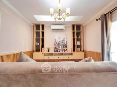 Elegant living room with modern chandelier and cozy sofa, featuring built-in shelves and air conditioning.