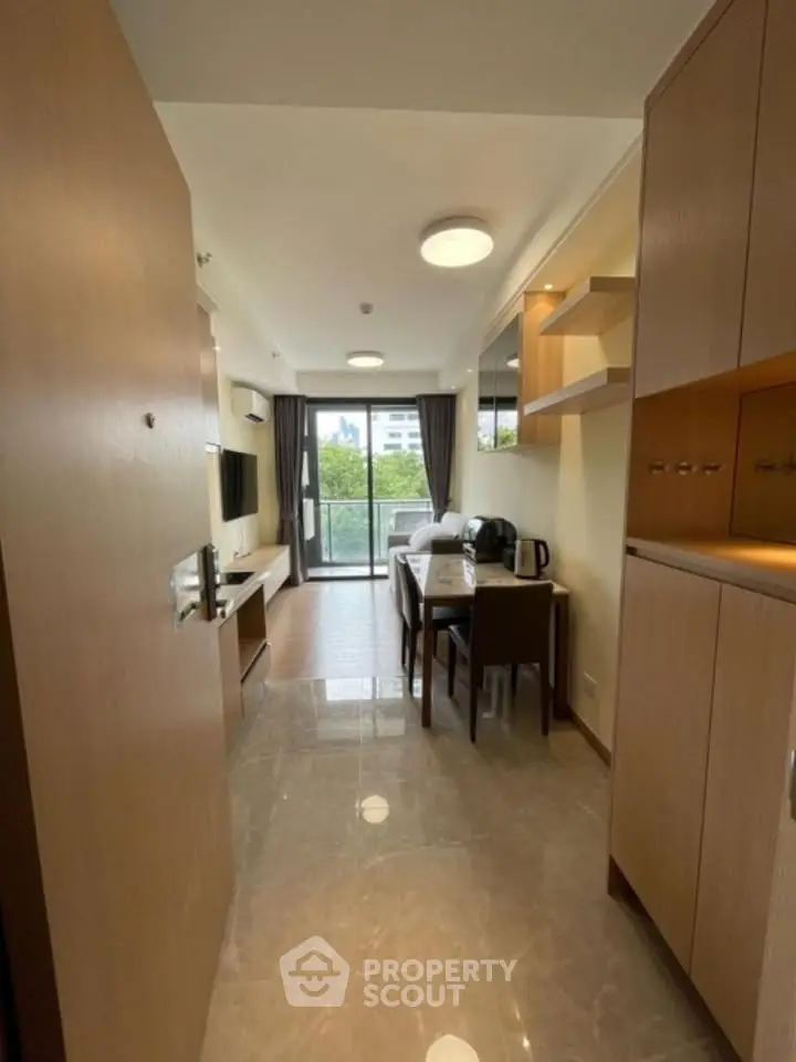 Modern apartment entrance leading to a cozy living area with dining table and balcony view.