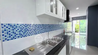 Modern kitchen with sleek countertops and vibrant blue tile backsplash, offering a bright and inviting cooking space.