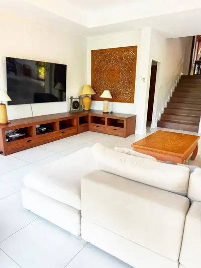 Spacious living room with modern decor and large TV, perfect for relaxation and entertainment.