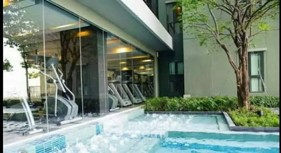 Modern gym with glass walls overlooking a serene outdoor pool and lush greenery.