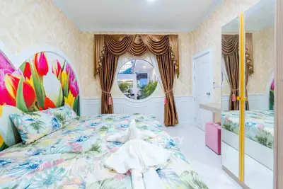 Luxurious bedroom with floral decor and elegant drapery, featuring a large mirror and vibrant bedding.