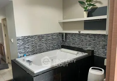 Luxurious bathroom with modern jacuzzi tub and stylish tile backsplash.