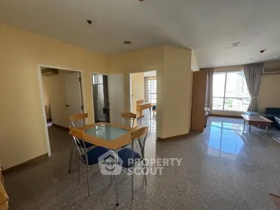 Spacious open-plan living area with large windows and modern dining set in a high-rise apartment.