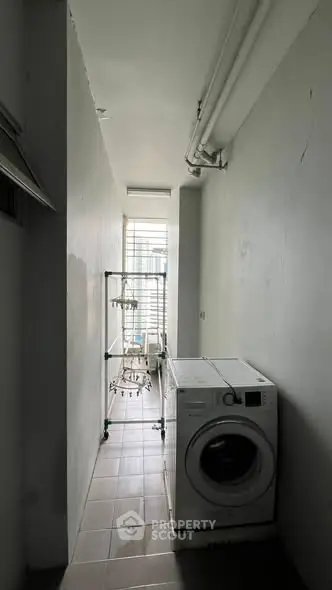 Compact laundry area with washing machine and drying rack in modern apartment.