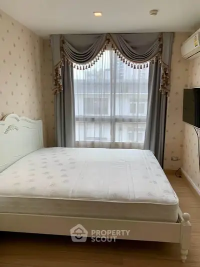 Charming bedroom with elegant drapes and natural light, featuring a cozy bed and wall-mounted TV.