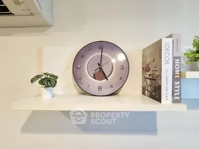 Stylish wall shelf with modern clock and decor books in a cozy living space.