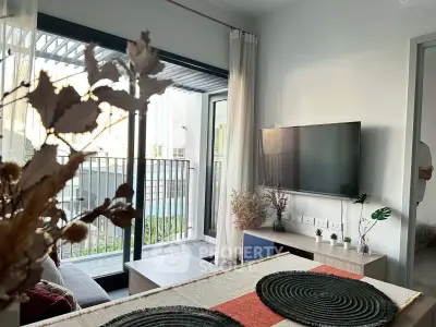Modern living room with balcony view, stylish decor, and wall-mounted TV in a contemporary apartment.
