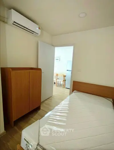 Cozy bedroom with wooden furniture and air conditioning, perfect for a comfortable living experience.