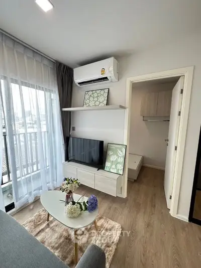 Modern living room with balcony, featuring sleek furniture and stylish decor in a cozy apartment setting.