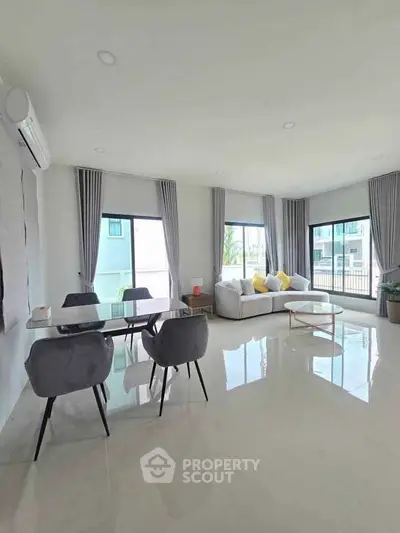 Spacious modern living room with large windows and elegant dining area, perfect for family gatherings.