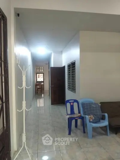 Spacious hallway with seating area in a residential property, featuring tiled flooring and natural light.