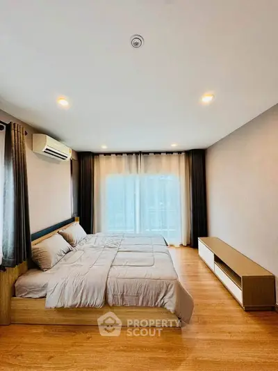 Spacious bedroom with modern decor and large window for natural light