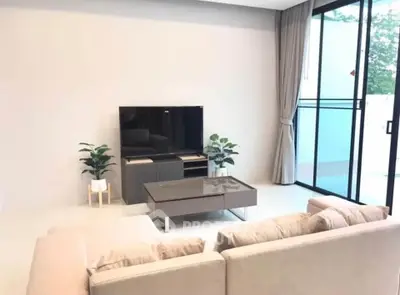 Modern living room with sleek furniture and large window offering natural light.
