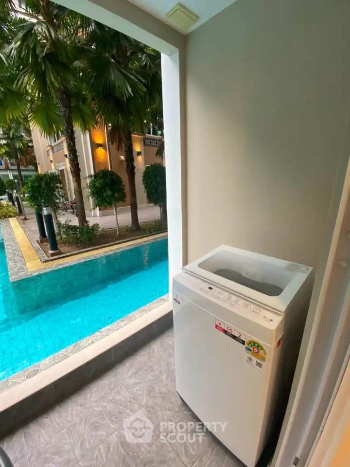 Charming poolside view with modern washing machine on a cozy balcony, perfect for urban living.