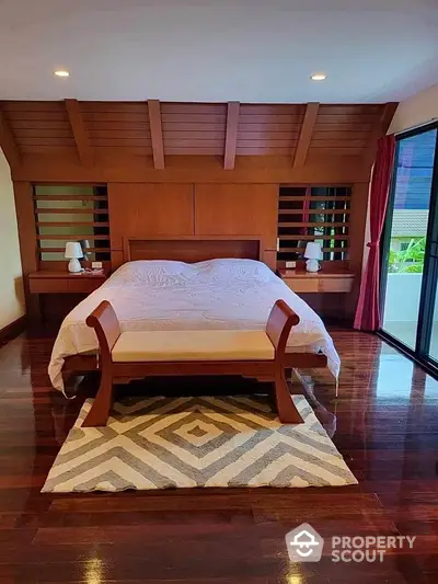 Luxurious bedroom with wooden accents and large windows for natural light.