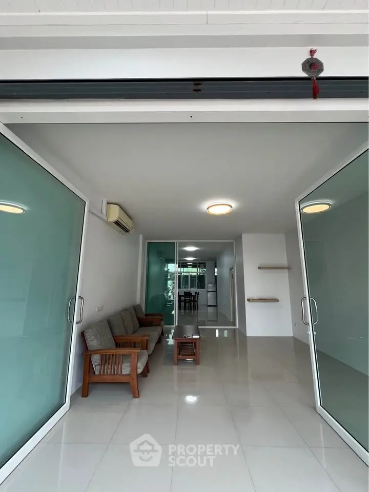 Spacious modern living room with glass doors and sleek furniture, perfect for contemporary living.