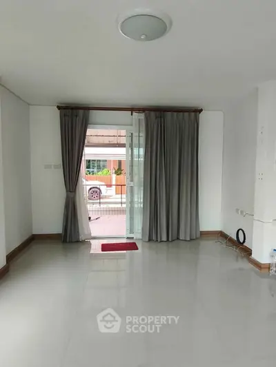 Spacious living room with large windows and modern curtains, offering a bright and airy atmosphere.