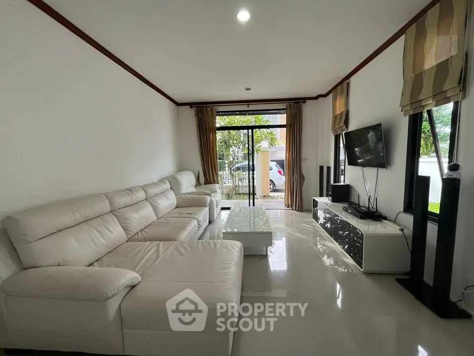 Spacious modern living room with white leather sectional sofa and large windows
