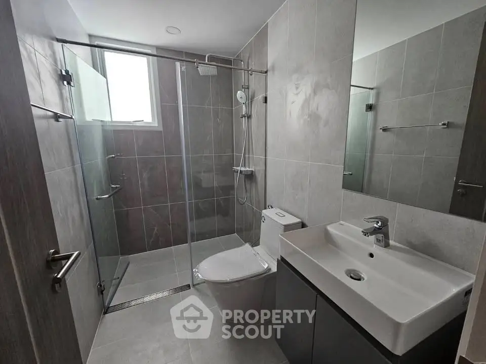 Modern bathroom with sleek fixtures and glass shower enclosure in a contemporary apartment.