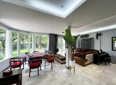 Spacious living room with large windows and garden view, featuring modern furniture and elegant decor.
