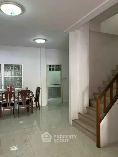 Spacious open-plan living area with dining set and staircase, ideal for family gatherings.