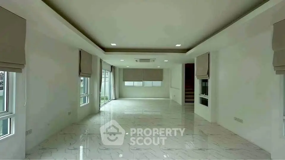 Spacious modern living room with marble flooring and large windows.