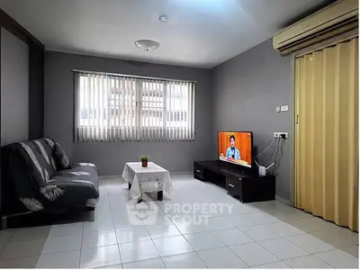 Cozy living room with modern decor, featuring a comfortable sofa, flat-screen TV, and air conditioning.