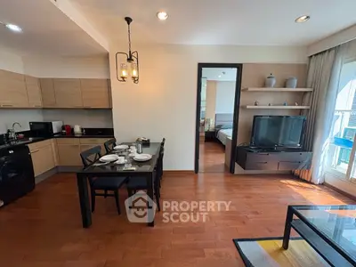 Modern open-layout living room with dining area and kitchen, featuring hardwood floors and stylish decor.