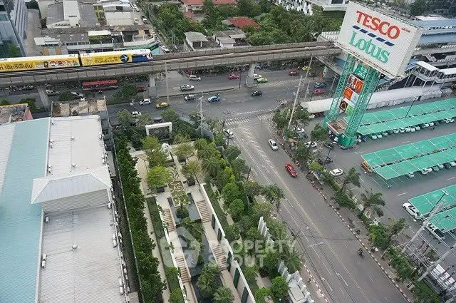 Aerial view of urban landscape with roads, greenery, and commercial areas.
