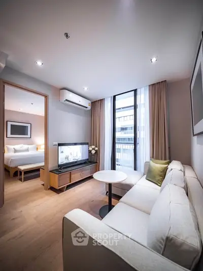 Modern living room with cozy sofa and view into elegant bedroom, featuring stylish decor and natural light.