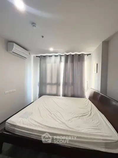 Cozy bedroom with air conditioning and natural light through large windows.